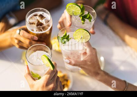 Group of people celebrating toasting with cocktails - cropped detail with focus on hands - lifestyle concept of people, drinks and alcohol - no faces Stock Photo