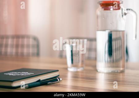 Swatches in pastel colors, notebook on wooden table and a jug of water, a glass.selective focus. Stock Photo