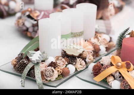 Advent candle holder or Advent wreath with four white candles in a row, green ribbons, pine cones and dried flowers for Christmas decoration Stock Photo