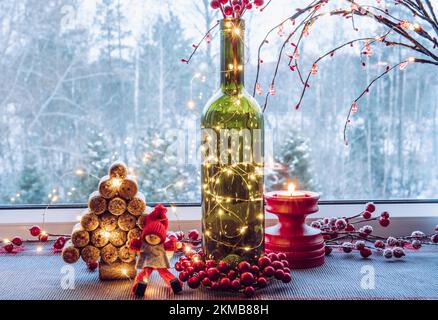Christmas decoration set with wine bottle filled with micro led party lights and spruce tree made with used wine corks, cute vintage elf figurine. Stock Photo
