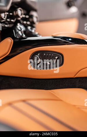 A vertical closeup of an Aston Martin Vantage interior with brown leather seat adjust buttons Stock Photo