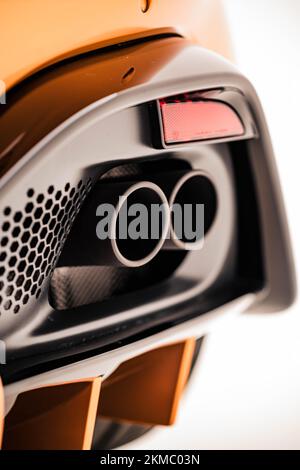 A vertical closeup of an Aston Martin Vantage exhaust pipes on a Golden Saffron background Stock Photo