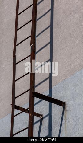 shadows from the stairs on the wall of the building in sunny bright weather, an old metal fire escape with shadows on the wall of the house Stock Photo
