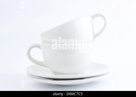WhWhite cups and saucers stacked on a white background. Copy spaceite cups and saucers stacked on a white background. Copy space Stock Photo