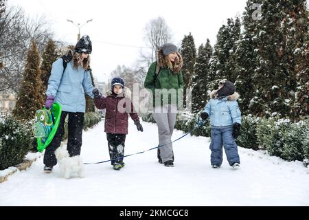 Outdoors winter activities for family, friends. Happy Family, friends, two women, two boy kids and dog, mothers and sons walking, having fun outdoors Stock Photo