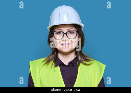 Female industrial construction worker in hardhat vest on blue background Stock Photo