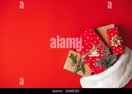 Santa Claus hat with gift boxes on red background. Christmas presents and santa hat on red background. Xmas gift ideas Stock Photo