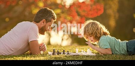 Father and son play chess outdoor, banner poster with copy space, fathers day. happy family. parenthood and childhood. checkmate. Stock Photo