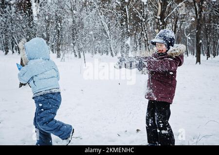 Fun games kids can play in the snow. Outdoor winter activities for kids and family. Happy kids having fun, running, playing snowball together at Stock Photo