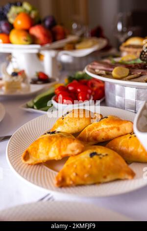 samsa on a white plate on the table with dishes and snacks. Stock Photo