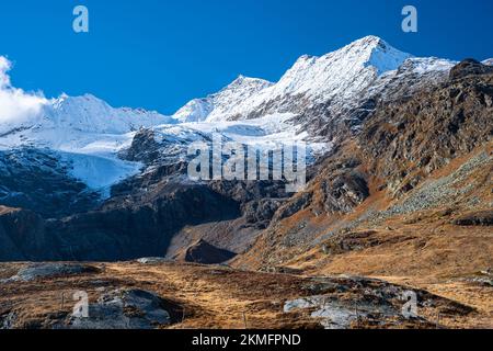 Barren alpine landscape in Graubünden canton, Switzerland in autumn. Snowcapped mountain Piz Bernina can be seen. Stock Photo