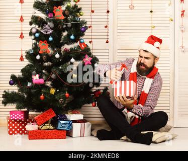 Santa Claus with disappointed face on wooden wall and red garlands ...
