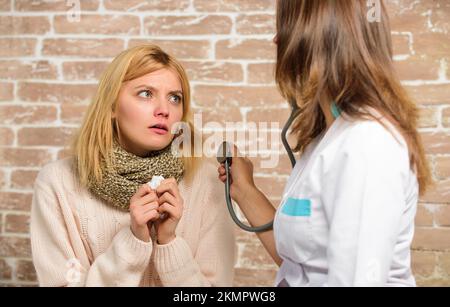 Girl in scarf hold tissue while doctor examine her. Cold and flu remedies. Recognize symptoms of cold. Remedies should help beat cold fast. Tips how Stock Photo