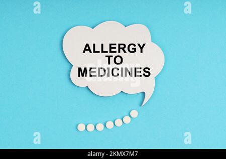 Medicine and health concept. On a blue table are pills and a white plate with the inscription - allergy to medicines Stock Photo