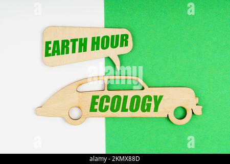 Environmental concept. On a white and green background, a wooden figure of a car with the inscription Ecology and a plate with the inscription - Earth Stock Photo