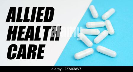 Medicine and health concept. There are pills on the blue surface, on the white surface it says - Allied Health Care Stock Photo
