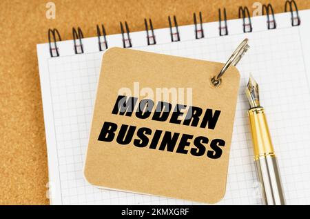 Business and economy concept. There are two notebooks and a pen on the table. On the top notepad, the inscription - Modern Business Stock Photo