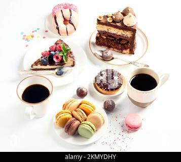 Table with various cookies, donuts, cakes, cheesecakes and coffee cups on white background.  Delicious dessert table. Stock Photo