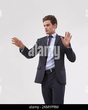 Controlling the digital world. A handsome young businessman interacting with a transparent digital interface. Stock Photo