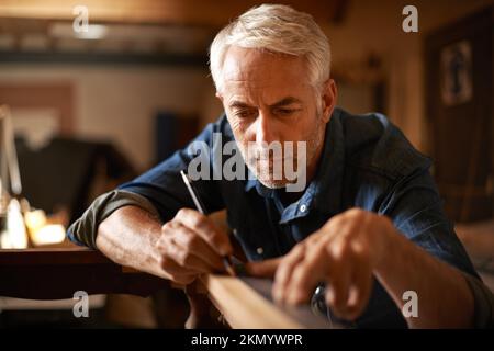 He had an eye for detail. a senior builder working on a project in his workshop. Stock Photo