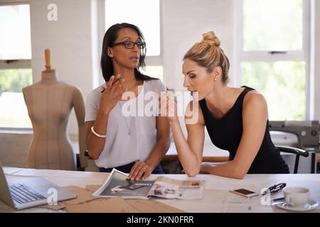 Putting their heads together on a new design project. a two attractive designers work on a layout. Stock Photo