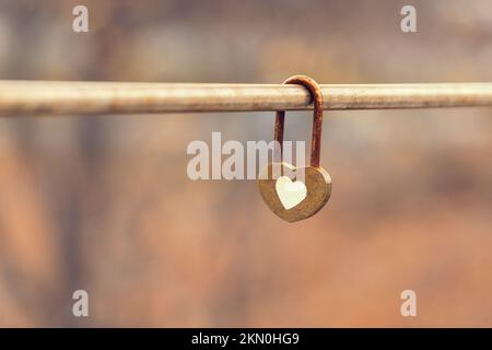 Heart shaped love lock hanging on bridge in autumn. Concept of love. Padlock on autumn background. Stock Photo