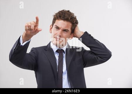 Wrapping his head around touchscreen technology. A handsome young businessman looking confused while interacting with a transparent digital interface. Stock Photo
