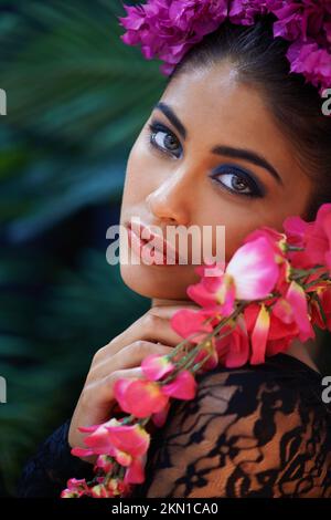 Eyes that hypnotize. A portrait of a beautiful woman wearing colorful flowers. Stock Photo