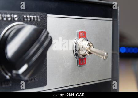 Vintage toggle switch set to on with blue lights in the background Stock Photo