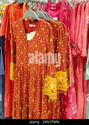 Female casual clothes in boutique, clothes with a selection of ladies fashion, Colorful women's dresses on hangers in a retail shop in India. Stock Photo