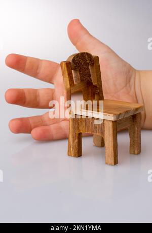 Child holding a brown color wooden toy chair on white background Stock Photo