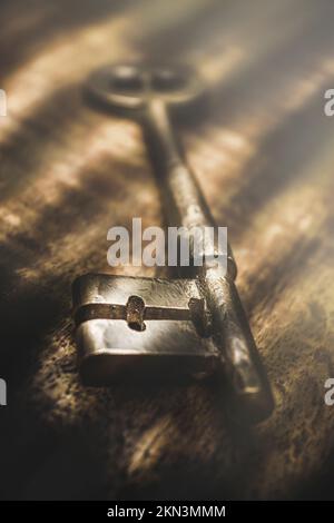 Still life photograph of a skeleton key placed in dark room, being lit by rays of blinding light. Unlocking the darkness makes the light brighter Stock Photo