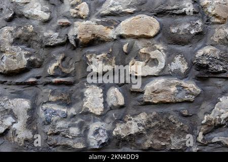 BACKGROUND TEXTURE - Wall constructed of irregular shaped dark stones Stock Photo