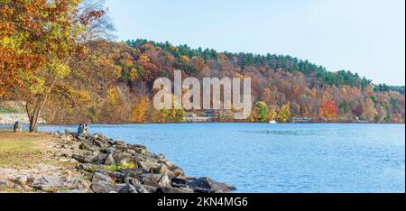 Scio, Ohio, USA- Oct. 24, 2022: Beautiful landscape of Tappan Lake in autumn color as viewed from the Harrison rest stop. Two fishermen fish off of th Stock Photo