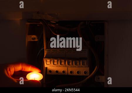 Blackout concept. Person's hand in complete darkness holding a holding a flashlight  to investigate a home fuse box during a power outage. Stock Photo