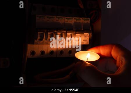 Blackout concept. Person's hand in complete darkness holding a holding a flashlight  to investigate a home fuse box during a power outage. Stock Photo