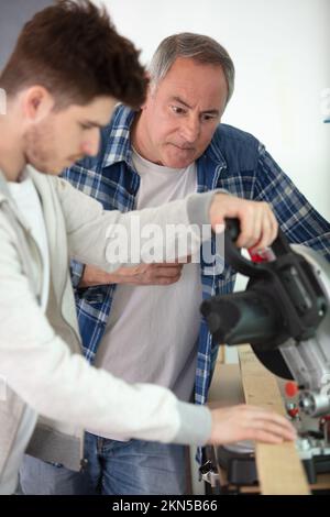 student and teacher in carpentry class using circular saw Stock Photo