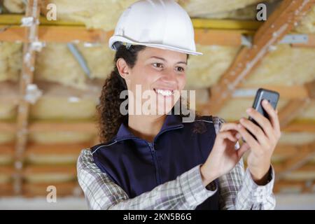 happy woman builder with blueprints using smart phone Stock Photo