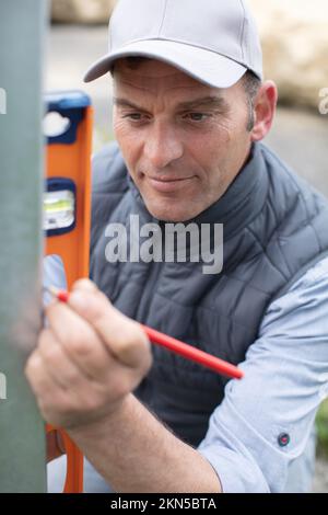 carpenter marking straight line on metal bar Stock Photo