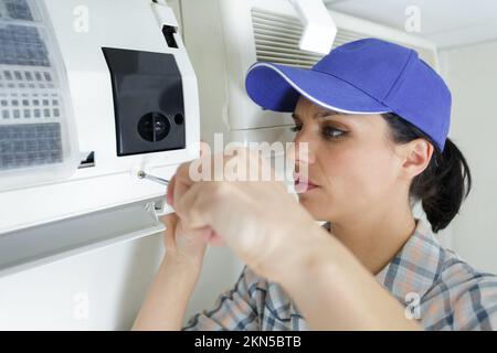 dark haired female electrician installing ac Stock Photo