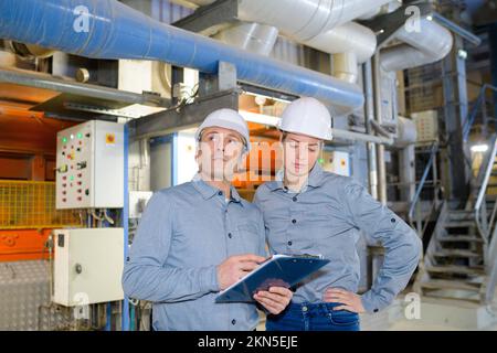 factory engineers operating hydraulic tube bender Stock Photo
