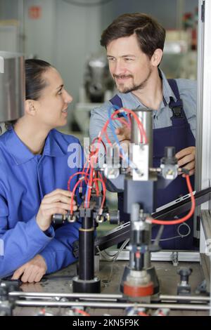 engineer and apprentice working on machine in factory Stock Photo