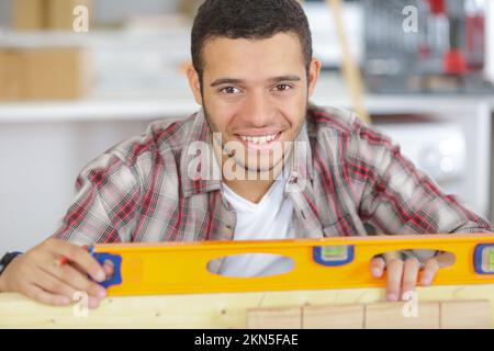 portrait of young handyman using spirit level Stock Photo
