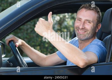 successful man sitting in car and showing thumbs up Stock Photo