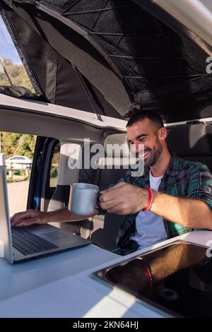 man working on his laptop from his camper van Stock Photo