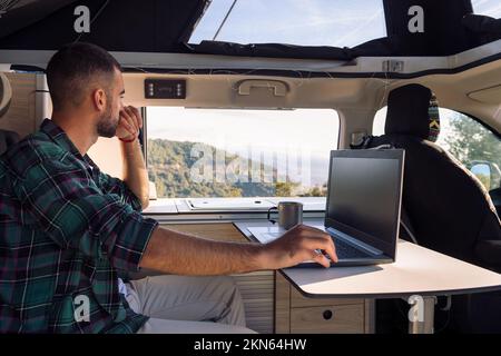 man working on his laptop from his camper van Stock Photo