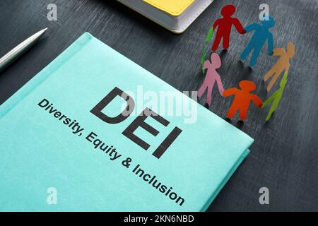 Book about DEI diversity, equity and inclusion and paper figurines. Stock Photo