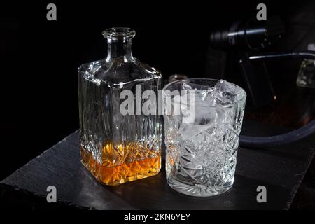 https://l450v.alamy.com/450v/2kn6yey/whisky-glass-decanter-with-whisky-liquor-and-an-empty-glass-of-whiskey-with-an-ice-on-slate-plate-smoke-machine-on-background-2kn6yey.jpg