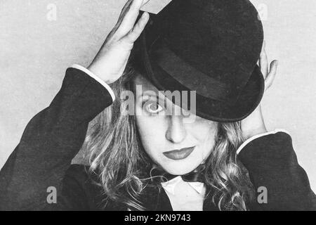 Rough textured image of a broadway entertainer holding vintage hat while looking at camera in a depiction of a cabaret theatre show Stock Photo