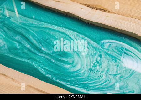 liquid turquoise epoxy on the kitchen table in the workshop Stock Photo
